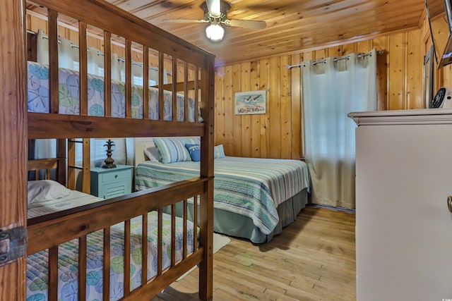 bedroom featuring wood ceiling, wood walls, ceiling fan, and light hardwood / wood-style flooring