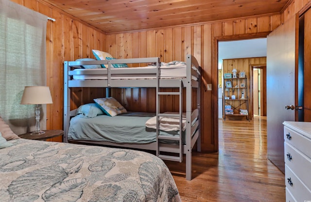 bedroom featuring light hardwood / wood-style flooring, wood ceiling, and wooden walls