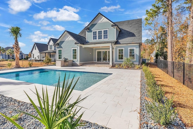 rear view of property featuring a patio and a fenced in pool