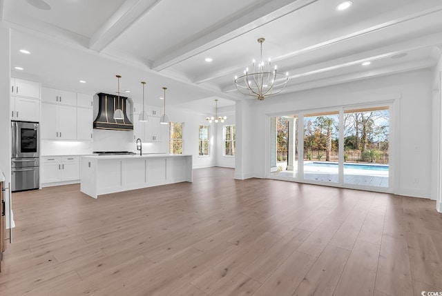 kitchen featuring premium range hood, beam ceiling, pendant lighting, light hardwood / wood-style floors, and white cabinetry