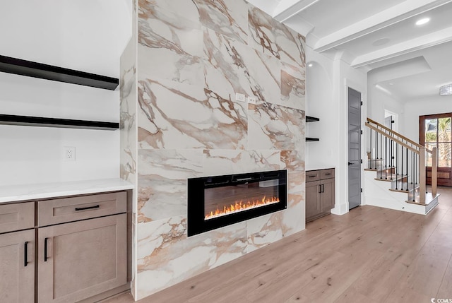 unfurnished living room featuring a fireplace, beamed ceiling, tile walls, and light wood-type flooring