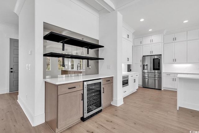 kitchen with ornamental molding, stainless steel appliances, beverage cooler, white cabinets, and light hardwood / wood-style floors