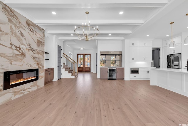 unfurnished living room featuring beamed ceiling, light hardwood / wood-style floors, a premium fireplace, and beverage cooler