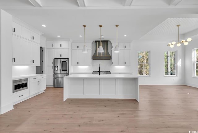 kitchen featuring beam ceiling, wall chimney exhaust hood, stainless steel appliances, light hardwood / wood-style floors, and decorative light fixtures