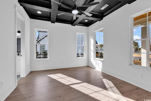 empty room with beamed ceiling, light hardwood / wood-style flooring, a wealth of natural light, and coffered ceiling