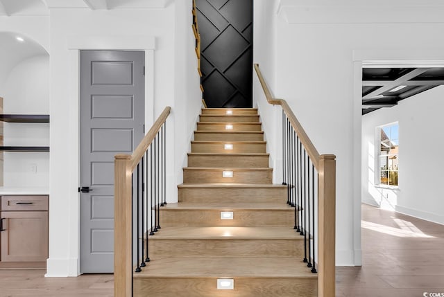 stairway with beamed ceiling, wood-type flooring, and coffered ceiling