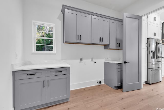 clothes washing area with cabinets, washer hookup, light hardwood / wood-style floors, and hookup for an electric dryer