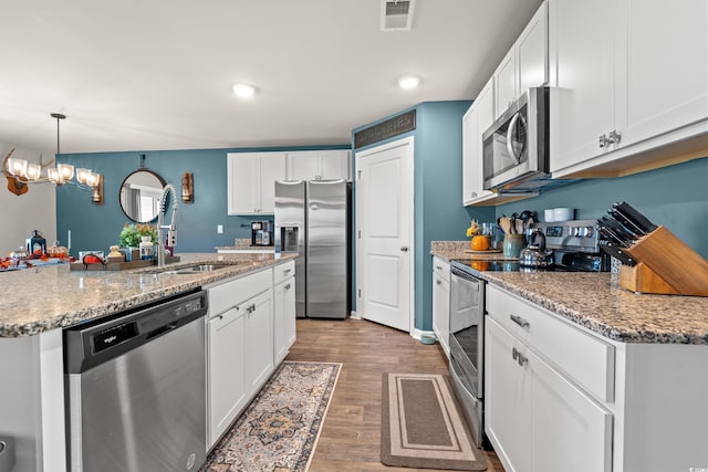 kitchen featuring white cabinets, hardwood / wood-style floors, hanging light fixtures, sink, and appliances with stainless steel finishes