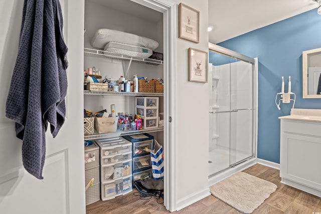 bathroom with walk in shower, wood-type flooring, and vanity