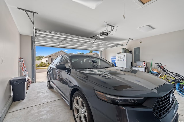 garage featuring a garage door opener, electric panel, and white refrigerator