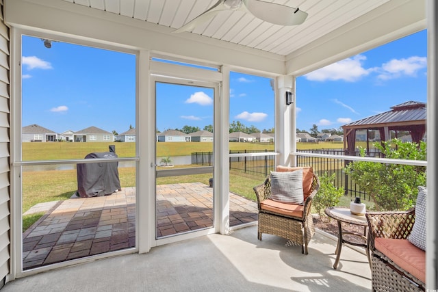 sunroom with a water view and ceiling fan