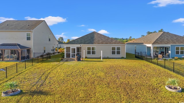 back of property featuring a lawn and a gazebo