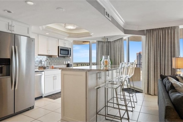 kitchen featuring white cabinetry, ornamental molding, appliances with stainless steel finishes, and a kitchen island