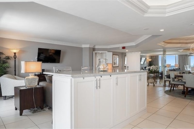 kitchen with white cabinetry, a kitchen island, ornamental molding, and a tray ceiling