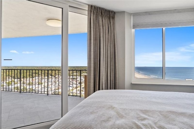 bedroom featuring multiple windows, a wall of windows, and a water view