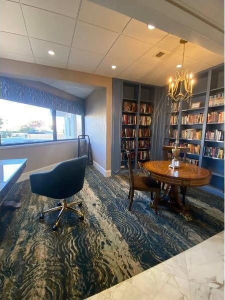 living area with a paneled ceiling, a chandelier, and built in features