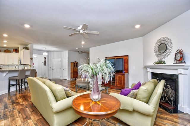 living room featuring dark hardwood / wood-style flooring, ceiling fan, and sink