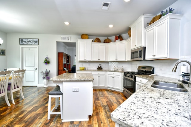 kitchen featuring a center island, sink, tasteful backsplash, white cabinetry, and stainless steel appliances