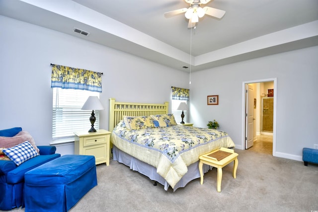 bedroom featuring multiple windows, ceiling fan, ensuite bathroom, and light carpet