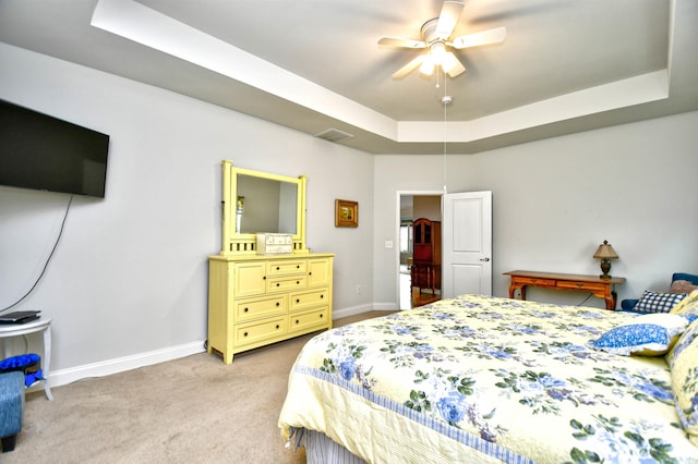 carpeted bedroom featuring a raised ceiling and ceiling fan