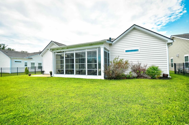 back of property featuring a lawn and a sunroom