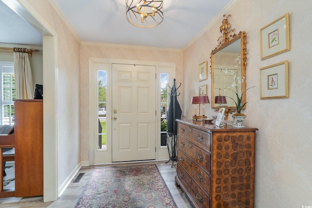 foyer entrance with crown molding, a chandelier, and light wood-type flooring