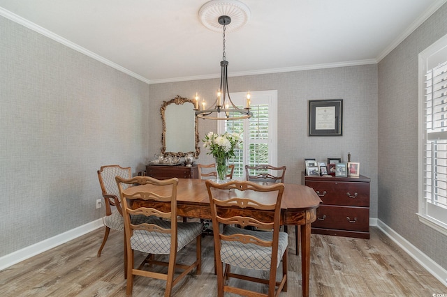 dining area featuring light hardwood / wood-style flooring, ornamental molding, a notable chandelier, and plenty of natural light