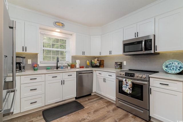 kitchen featuring crown molding, white cabinetry, light hardwood / wood-style flooring, and stainless steel appliances