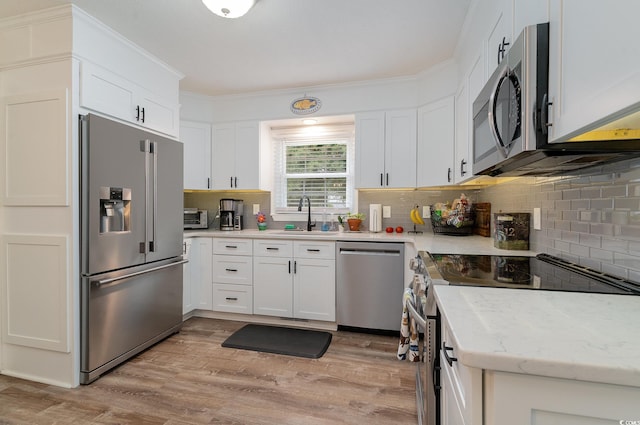 kitchen featuring appliances with stainless steel finishes, tasteful backsplash, light wood-type flooring, and white cabinets