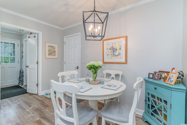 dining space featuring light hardwood / wood-style floors, crown molding, and an inviting chandelier