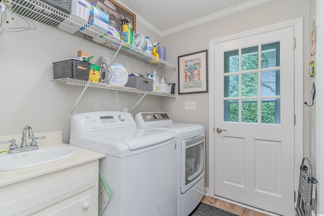 clothes washing area featuring ornamental molding, hardwood / wood-style floors, sink, a textured ceiling, and washing machine and dryer