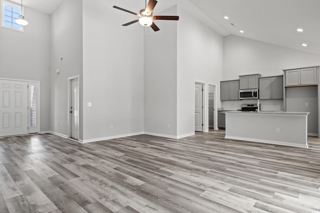 unfurnished living room featuring ceiling fan, high vaulted ceiling, and light hardwood / wood-style flooring