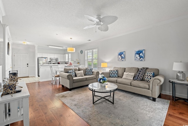 living room featuring ceiling fan, a textured ceiling, light wood-type flooring, and ornamental molding