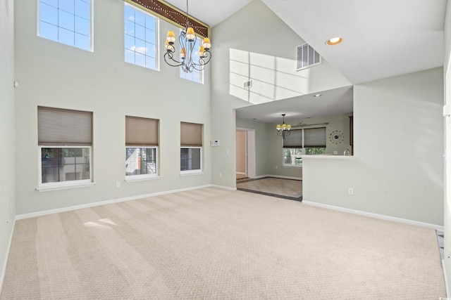 unfurnished living room featuring carpet floors, an inviting chandelier, and a towering ceiling