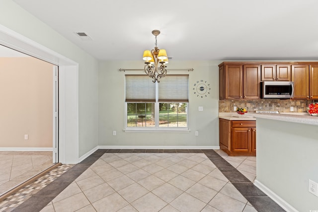 kitchen featuring an inviting chandelier, hanging light fixtures, light tile patterned floors, and tasteful backsplash