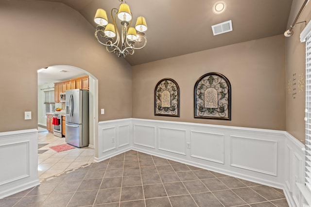 spare room featuring tile patterned flooring, vaulted ceiling, and a chandelier