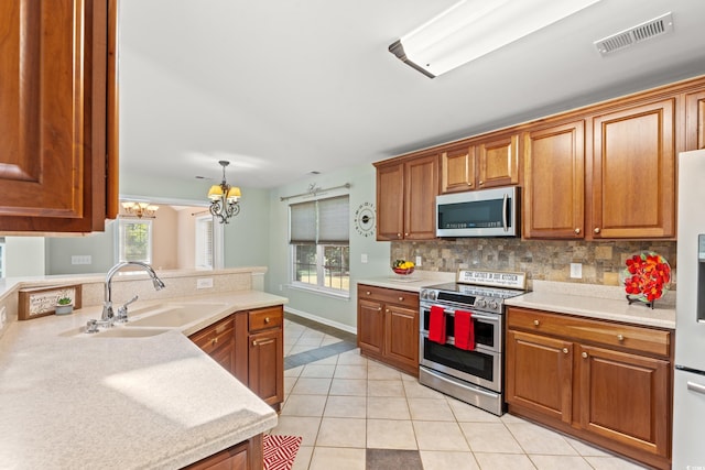 kitchen featuring light tile patterned floors, stainless steel appliances, an inviting chandelier, decorative light fixtures, and sink