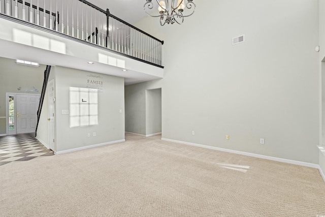 unfurnished living room with a notable chandelier, a high ceiling, and carpet