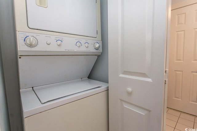 laundry area with stacked washing maching and dryer and light tile patterned flooring