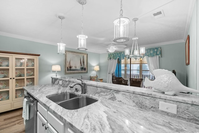 kitchen featuring sink, dishwasher, light stone countertops, crown molding, and hardwood / wood-style floors