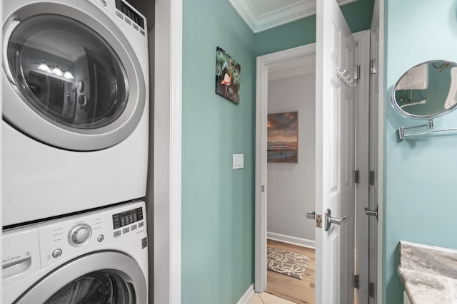 washroom with light hardwood / wood-style flooring, crown molding, and stacked washing maching and dryer