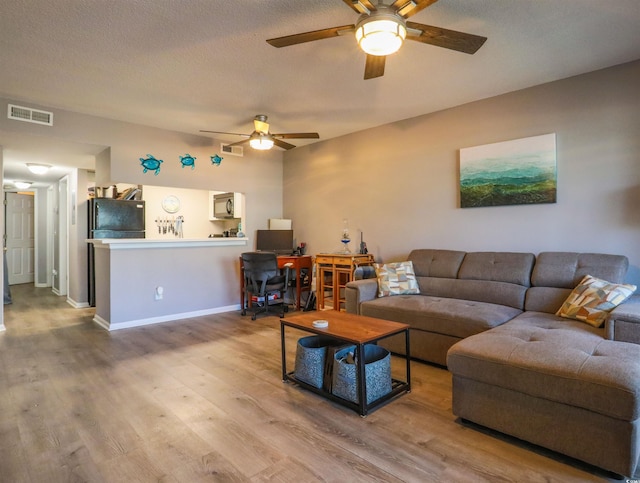 living room with ceiling fan, hardwood / wood-style floors, and a textured ceiling