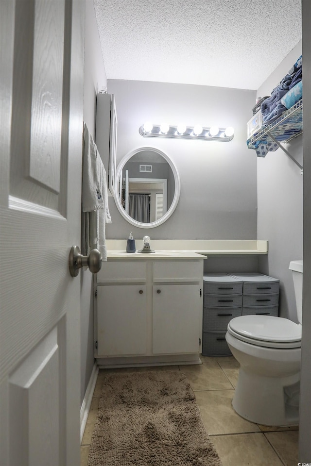 bathroom with tile patterned flooring, a textured ceiling, vanity, and toilet