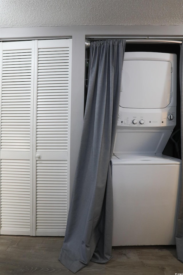 laundry room featuring stacked washer and dryer and dark hardwood / wood-style flooring