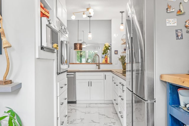 kitchen featuring white cabinetry, sink, stainless steel appliances, and decorative light fixtures