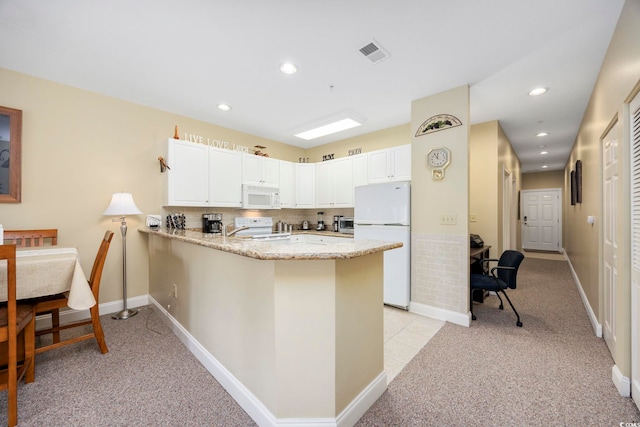 kitchen featuring white appliances, kitchen peninsula, light colored carpet, and white cabinetry