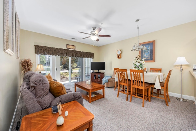 living room featuring ceiling fan with notable chandelier and carpet floors