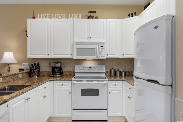 kitchen with sink, white appliances, white cabinetry, dark stone countertops, and decorative backsplash