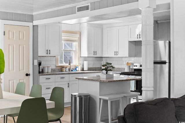 kitchen featuring dark stone counters, stainless steel appliances, and white cabinetry