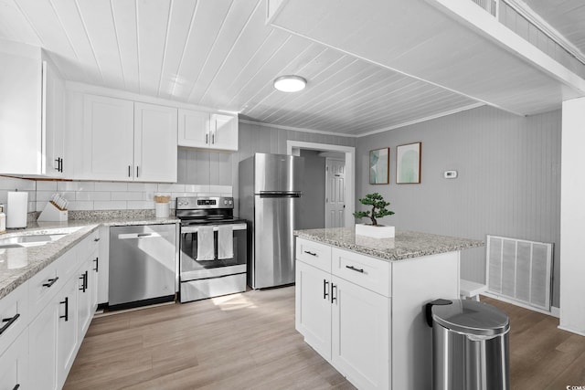 kitchen featuring light stone countertops, stainless steel appliances, white cabinetry, and light hardwood / wood-style floors